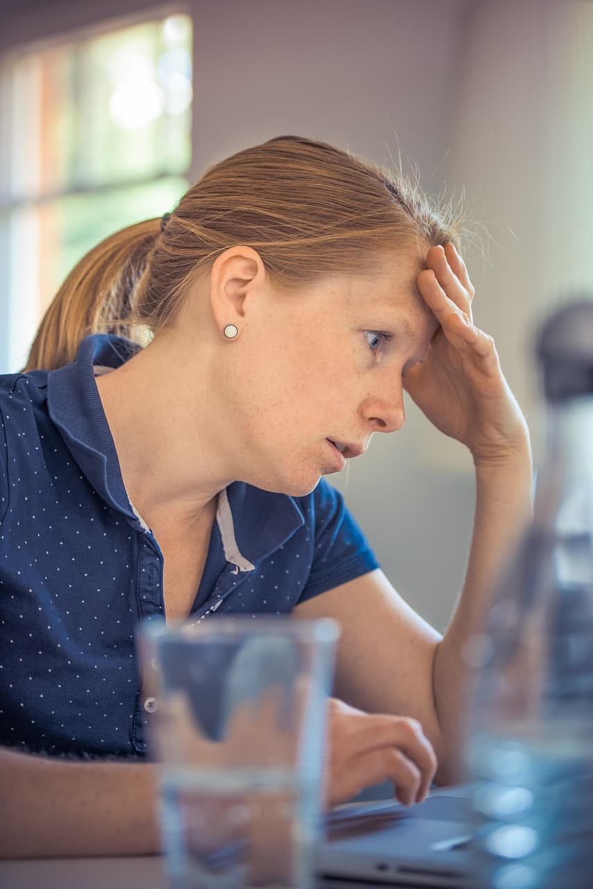A person at her laptop with her head resting in her hand